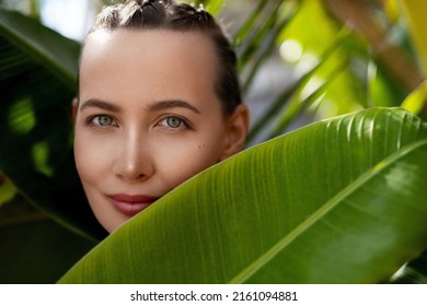 Green Beauty Portrait. Beautiful Young Woman With Braided Hair Against Fresh Green Tropical Palm And Banana Leafs. Organic Cosmetic Concept.