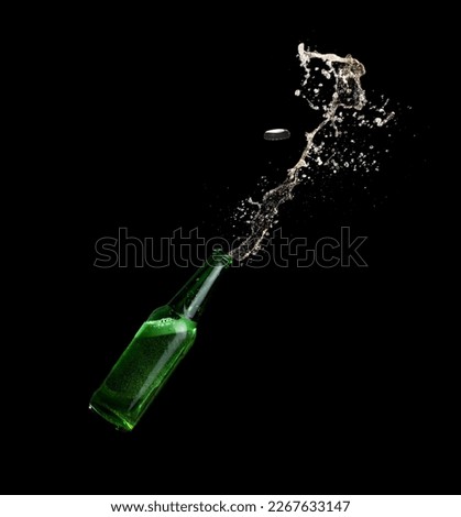 Green beer bottle opening with exploding and splashing on dark background