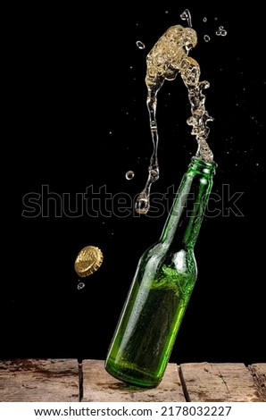 Green beer bottle up and splash on black background