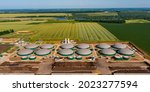 Green biogas plant storage tanks. Aerial view over biogas plant and farm in green fields. Renewable energy from biomass. Modern agriculture concept
