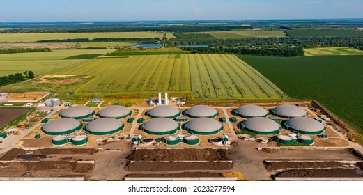 Green biogas plant storage tanks. Aerial view over biogas plant and farm in green fields. Renewable energy from biomass. Modern agriculture concept