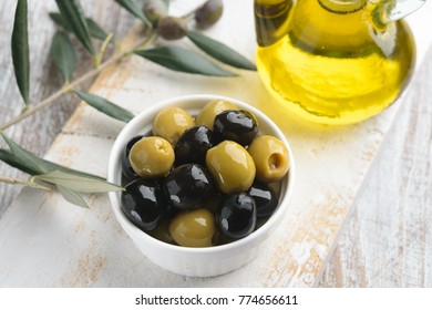 Green And Black Olives With Olive Oil, Rustic Wooden Board. 