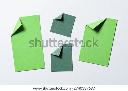 Green blank paper message notes or sheets with folded edge dog-ear earmark and copy space for text on white background, top view flat lay conceptual desk backdrop