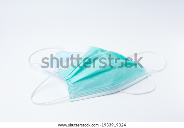 Green and blue\
disposable surgical face mask dirty top view. Mask protective\
coronavirus isolated on white background with copy space.\
Healthcare medical hygiene\
concept.