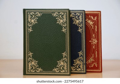 Green, blue and red cover vintage books bound in leather with golden details stacked on the bookshelf - Powered by Shutterstock