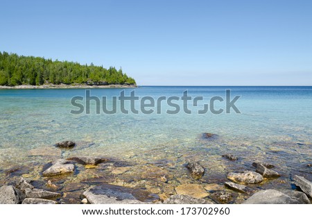 Green and blue water of Huron Lake, Ontario under blue sky.