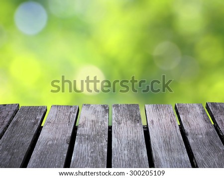 Green blurred background and brown wooden floor.  Soft focus on floor