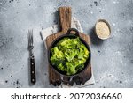 Green boiled broccoli cabbage in pan. Gray background. Top view