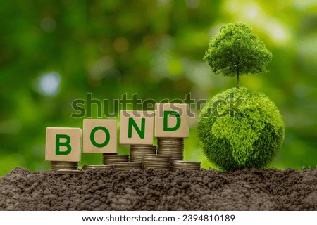Green bonds concept. Words BOND on a wood block place on coin stack and Green Globe with tree on top. Investment on bonds, Raising funds to fund environmentally friendly projects.green investment.