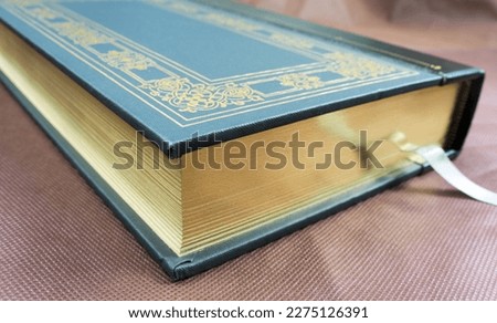 A green book with a gold plated edge
