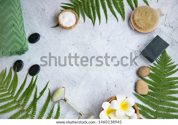 Green botanical\
spa flatlay with fern, charcoal soap, massage stones, frangipani\
flowers and bath salt , spa still life frame setting with copy\
space and body care\
products