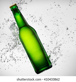 Green bottle of beer falling into water on white background
