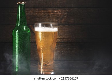 Green Bottle And Glass Of Cold Pale Lager Beer Over Wooden Background