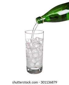 Green Bottle Pouring Water In Glass Of Cold Mineral Carbonated Water With Ice Cubes Isolated On White Background