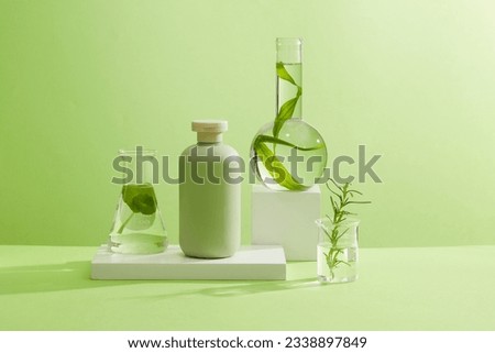 A green bottle unlabeled on white podiums with laboratory flask containing rosemary leaves, gotu kola and seaweed on green background. Mockup scene for advertising. Concept for organic cosmetic