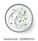 Green bowl of sour cream dip sauce with herbs isolated on white background, top view