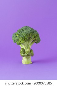 Green broccoli with muscle arms on bright purple background. Creative minimal concept. - Shutterstock ID 2000375585