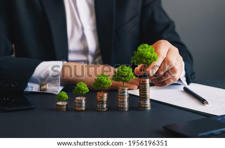 Green business growth. Businessman holding coin with tree growing on money coin stack. Finance sustainable development. 