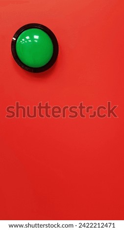 Green button on red wall placed at the top left.big green buzzer on vibrant red wall