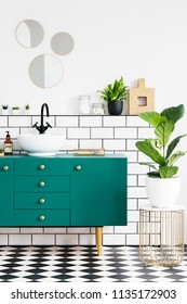 Green Cabinet Next To Plant On Gold Table In Modern Bathroom Interior With Mirrors. Real Photo