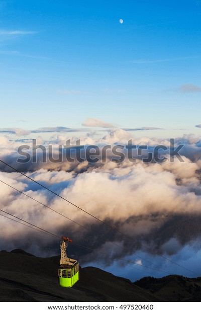 Green cable car in the\
mountains 