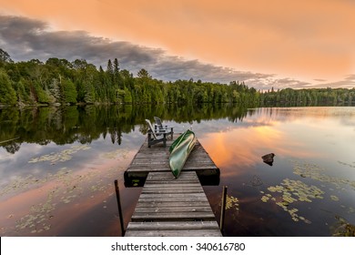 Green Canoe and Chairs on a Dock Next to a Lake at Sunset - Haliburton Highlands, Ontario, Canada