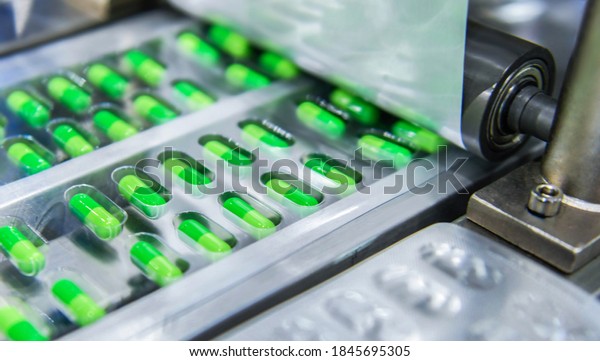 Green capsule medicine pill production line,\
Industrial pharmaceutical\
concept