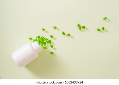 green capsules spilling out of a bottle