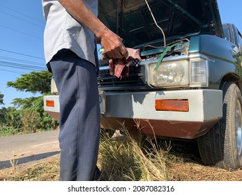 The Green Car Broke Down On The Side Of The Road.  Asian Elderly Man Repairing A Car