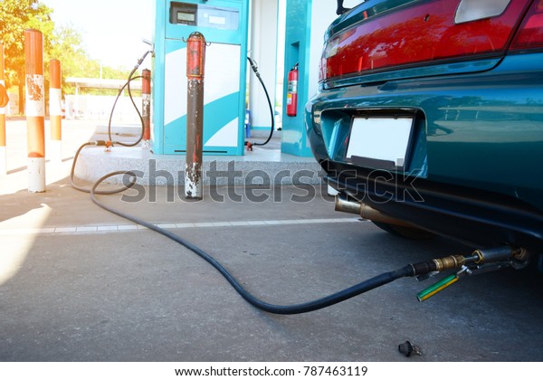 the green car and\
sun light in the gas LPG station with the black rubber tube from\
the fuel supply unit