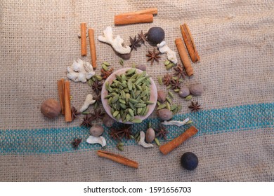 Green cardamom pods with cinnamon sticks and ginger on the background of burlap yarns - Powered by Shutterstock