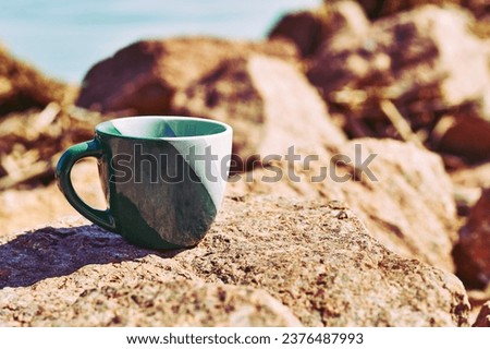 Green ceramic cups, coffee tea beverages on the shore of a stone rocky sea bay                                