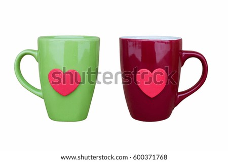 Green ceramic mug and maroon ceramic mug decorated with red heart, on white background, close-up