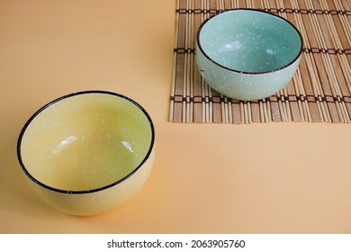 A green ceramic rice bowl was placed on a saucer, but a yellow rice bowl was placed on the floor. - Powered by Shutterstock