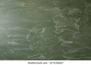 Green chalk board with abstract and partly smudged white  pattern on it.