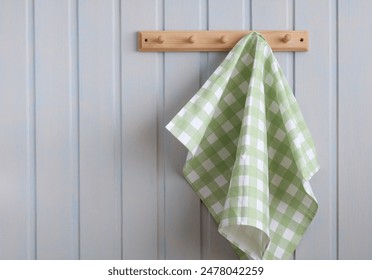 A green checkered kitchen towel hangs on a wooden hanger on a white board wall. the concept is without plastic. the interior of a white cottage. - Powered by Shutterstock