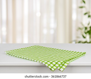 Green checkered kitchen towel on table over defocused curtain background
