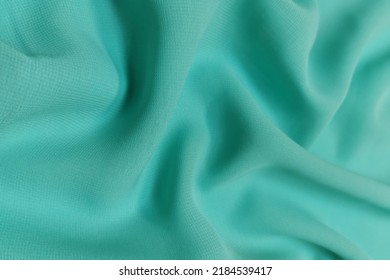 Green chiffon fabric crumpled or wavy fabric texture background. Abstract linen cloth soft waves. Silk yarn. Smooth elegant luxury cloth texture. Concept for banner or advertisement.