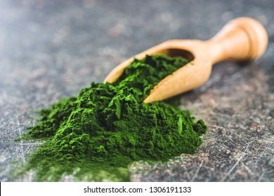 Green Chlorella Powder In Wooden Scoop.