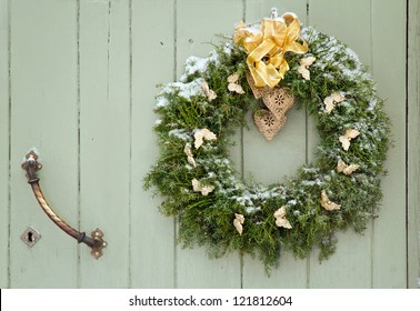 Green Christmas Wreath With A Golden Bow On A Wooden Green Rustic Door