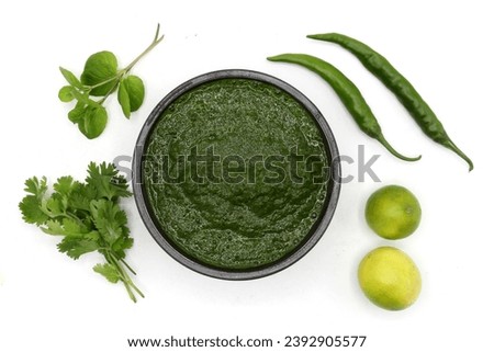 Green Chutney in black ceramic bowl with Mint Coriander lemon green chili top view isolated on white background