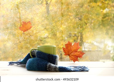 green circle in the scarf, the window with maple leaves and drops after rain in autumn / season when you need warm drinks - Shutterstock ID 493632109