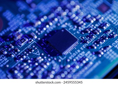 Green circuit board with a black integrated circuit chip and various small electronic components. It represents technology, hardware, and electrical engineering.