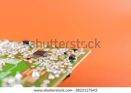 Green circuit board with chipset in surface, orange color background 