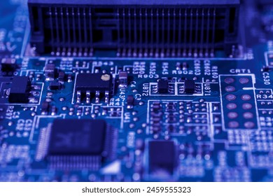 Green circuit board with various electronic components such as capacitors, resistors, and integrated circuits. These components are intricately arranged on the board - Powered by Shutterstock