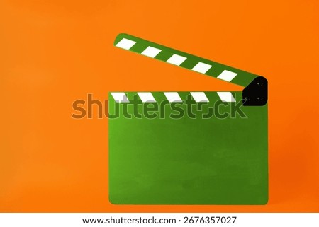 Green clapper board on orange background, space for text. Film industry