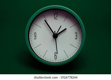Green clock on dark green background.  Sustainability concept. Save the world concept. World Earth Day concept.                          