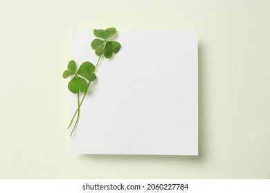 Green clover leaves and blank card on light background, top view. Space for text - Shutterstock ID 2060227784