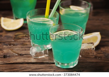 Green cocktail with lemon and ice on the wooden table, selective focus
