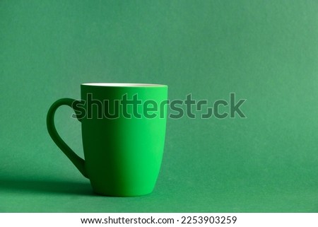 Green coffee or tea mug on green background. Space for text. Festive monochrome banner for design. Mock up for Patricks day.